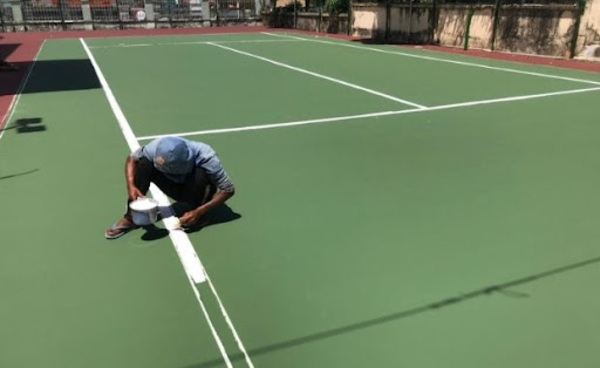 Người thợ đang tiến hành các bước kẻ các đường cơ bản trên sân tennis